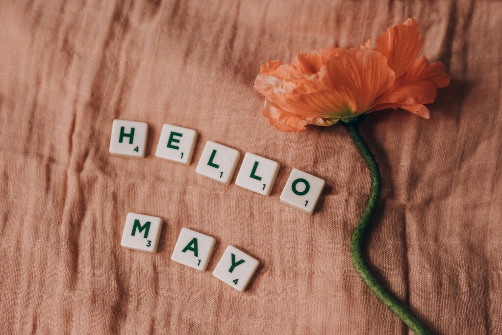 A photos saying Hello May in tiles with an orange flower.