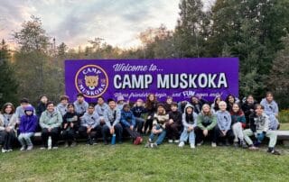 sep2026-camp-01 Students gathered in front of the Welcome to Camp Muskoka sign