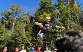 sep2026-camp-05 A student flying along the zipline above the trees