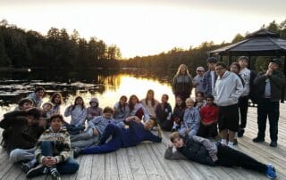 sep2026-camp-14 Students relaxing on the dock by the lake at sunset