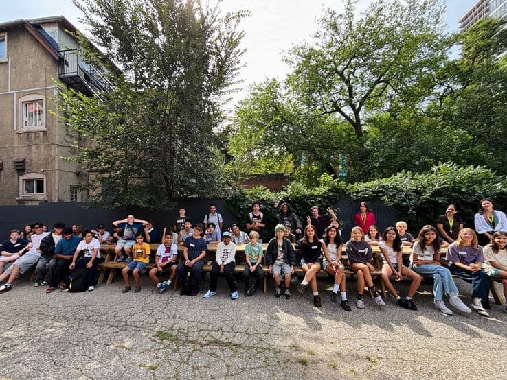 The whole student group seated together outside the school